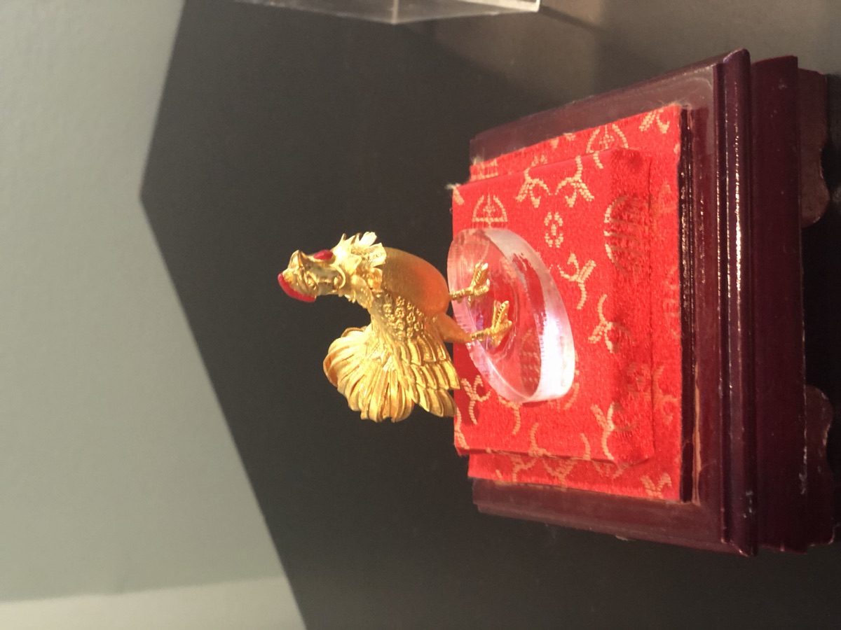 Golden zodiac rooster figurine on a red silk stand